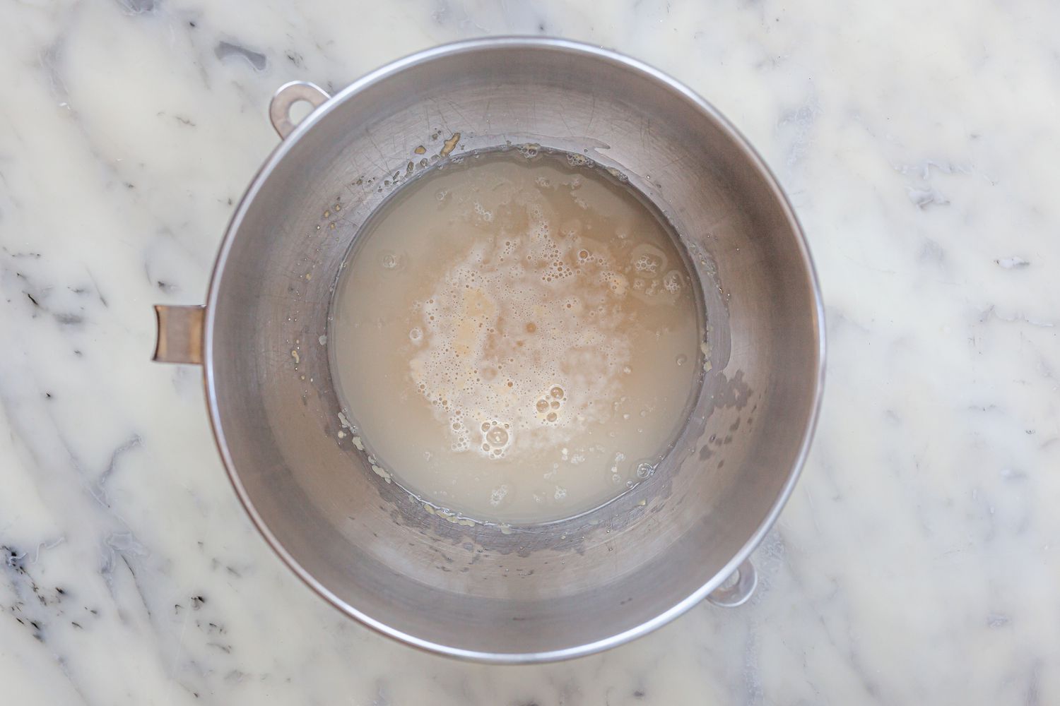 Mixing a pizza dough recipe in the bowl of a stand mixer.
