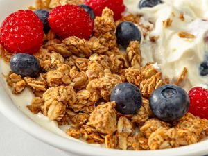 Closeup view of a bowl of granola topped with blueberries, strawberries and yogurt