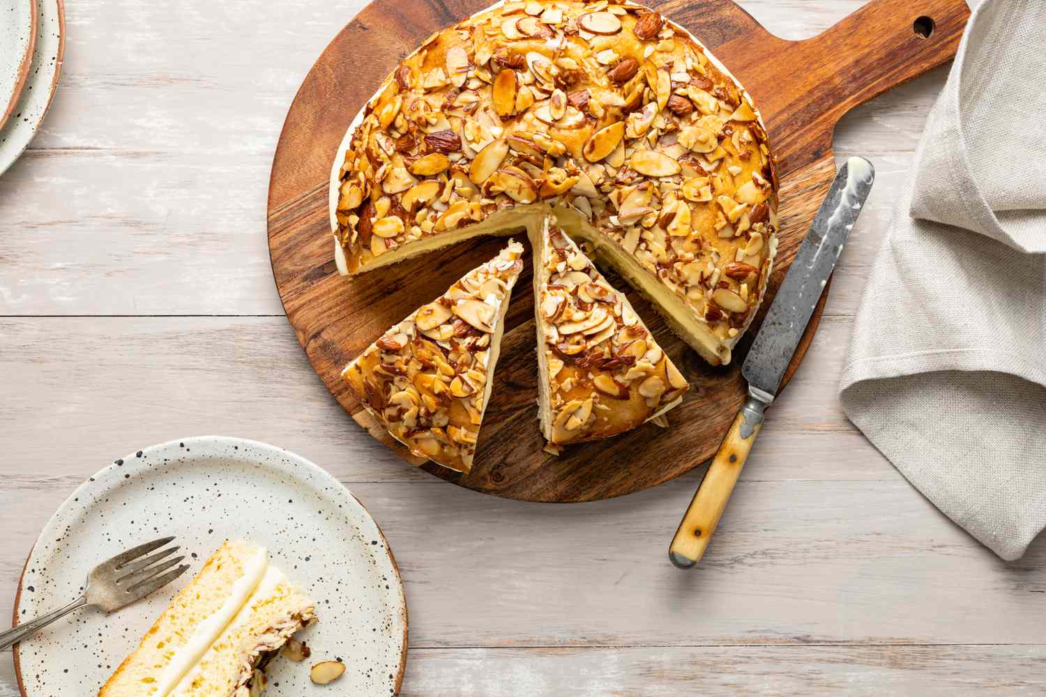 Bee Sting Cake on a Circular Wooden Board Sliced into Pieces with One Piece on a Plate