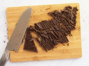 Chopped chocolate and a knife on a wooden cutting board