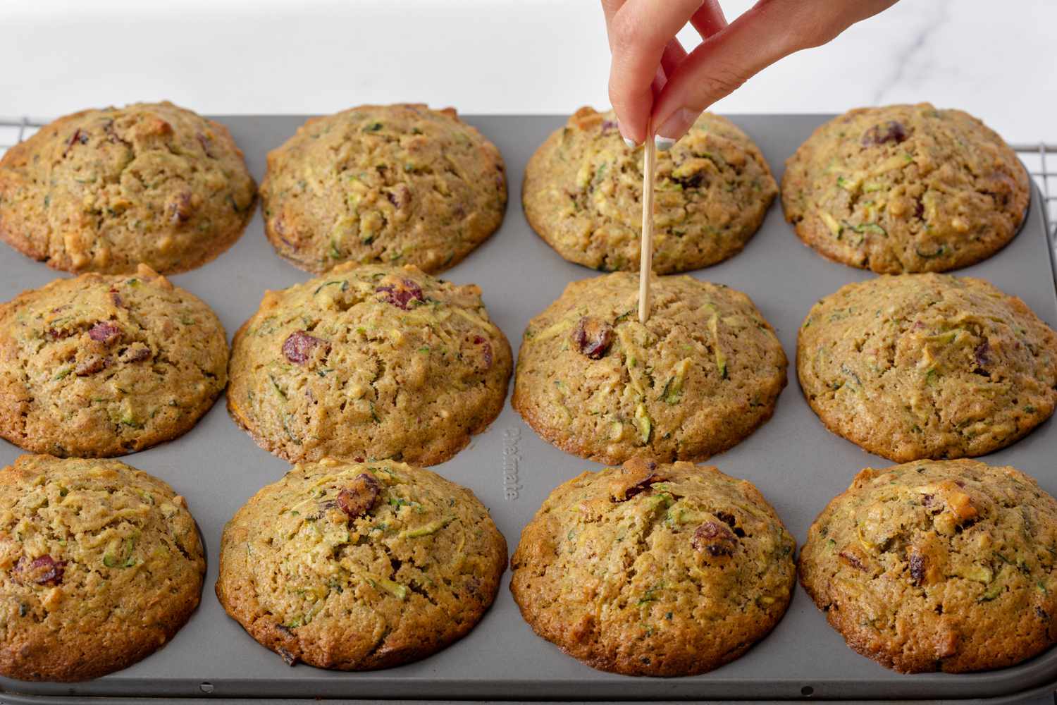 Testing for doneness for zucchini muffins out of the oven.