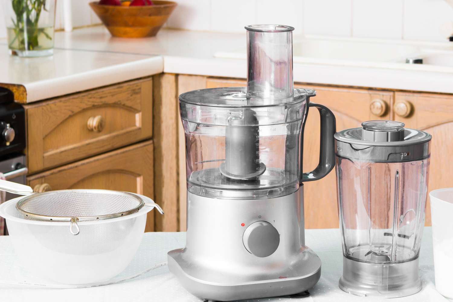 A food processor sieve and blender jar on a kitchen counter
