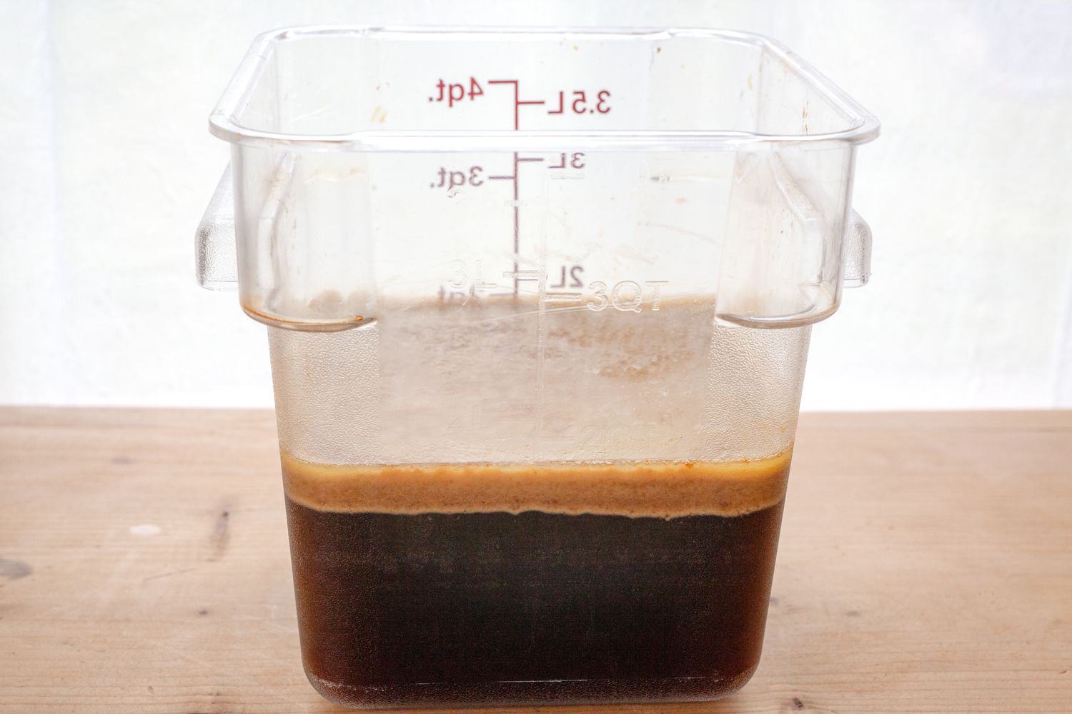 A container with separated brown liquid layers used for preparing a makeahead gravy