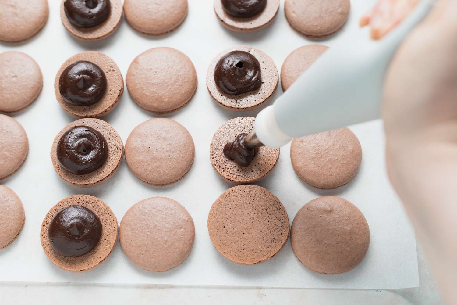 Piping ganache onto bottom of macaron shell.