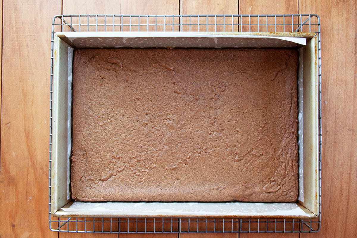 Unfrosted Gingerbread Bars in a lined baking pan and cooling on a cooling rack.