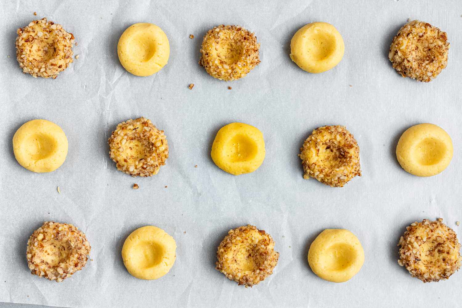 Thumbprint cookies on a cookie sheet and ready to be filled.