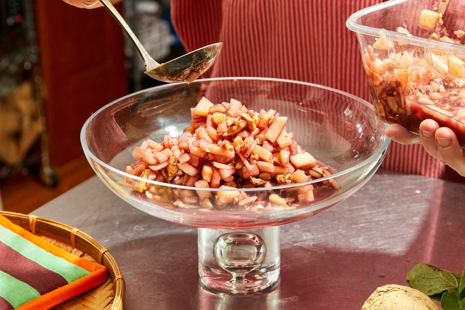 Charoset being spooned into a glass dish with a silver spoon