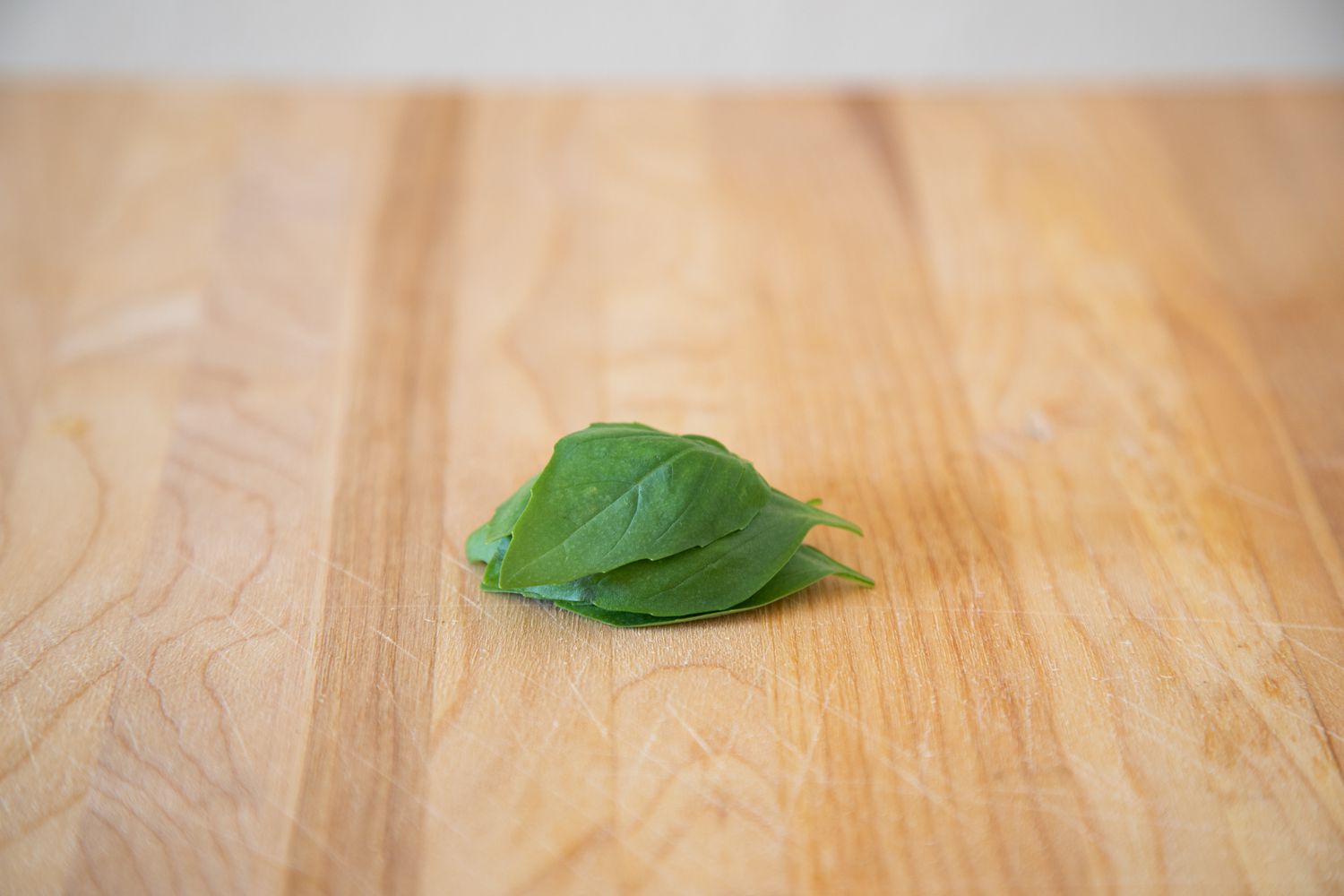 Pile of basil leaves on a wood cutting board