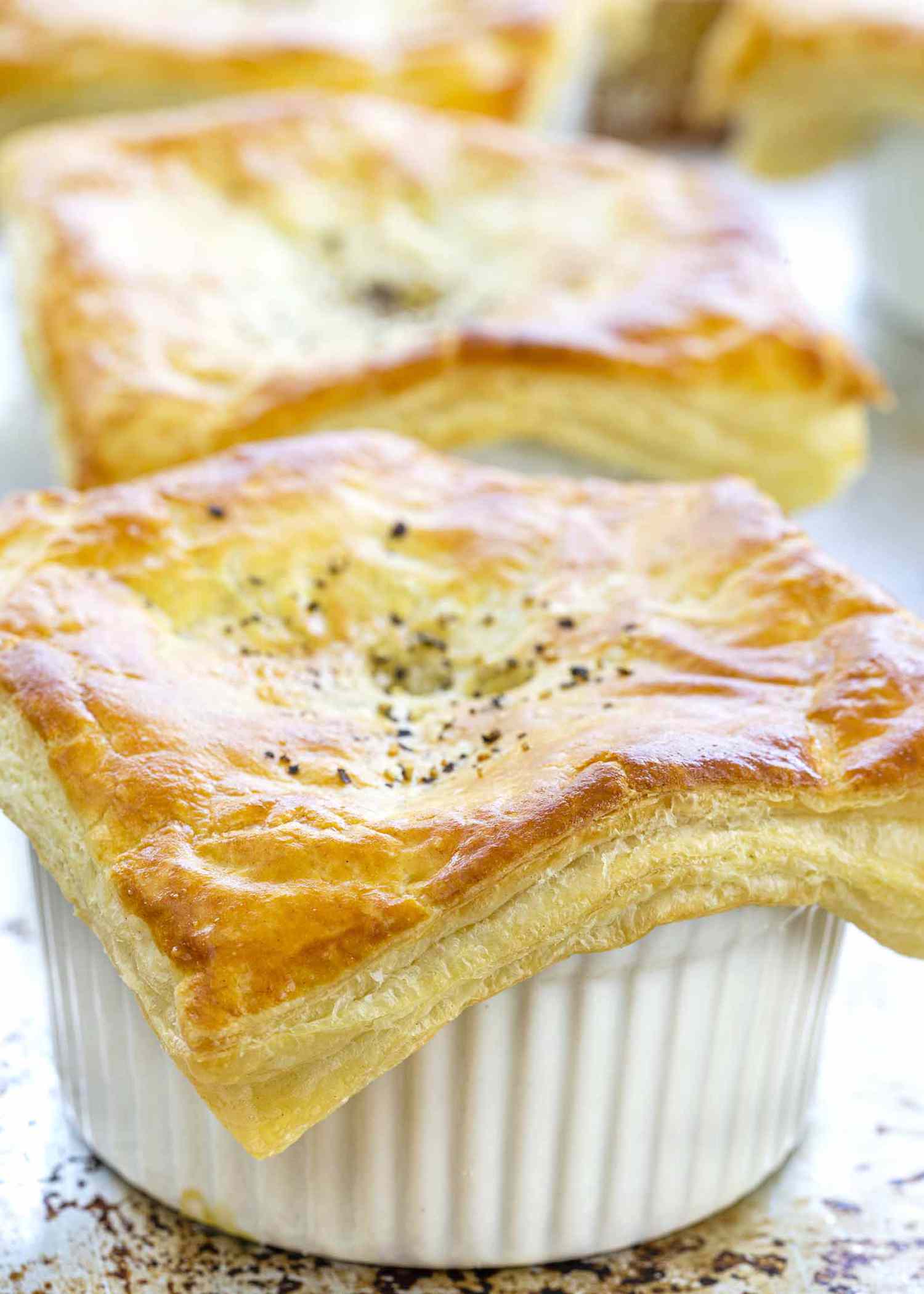 Vegetable pot pie on white plate with puff pastry on top.