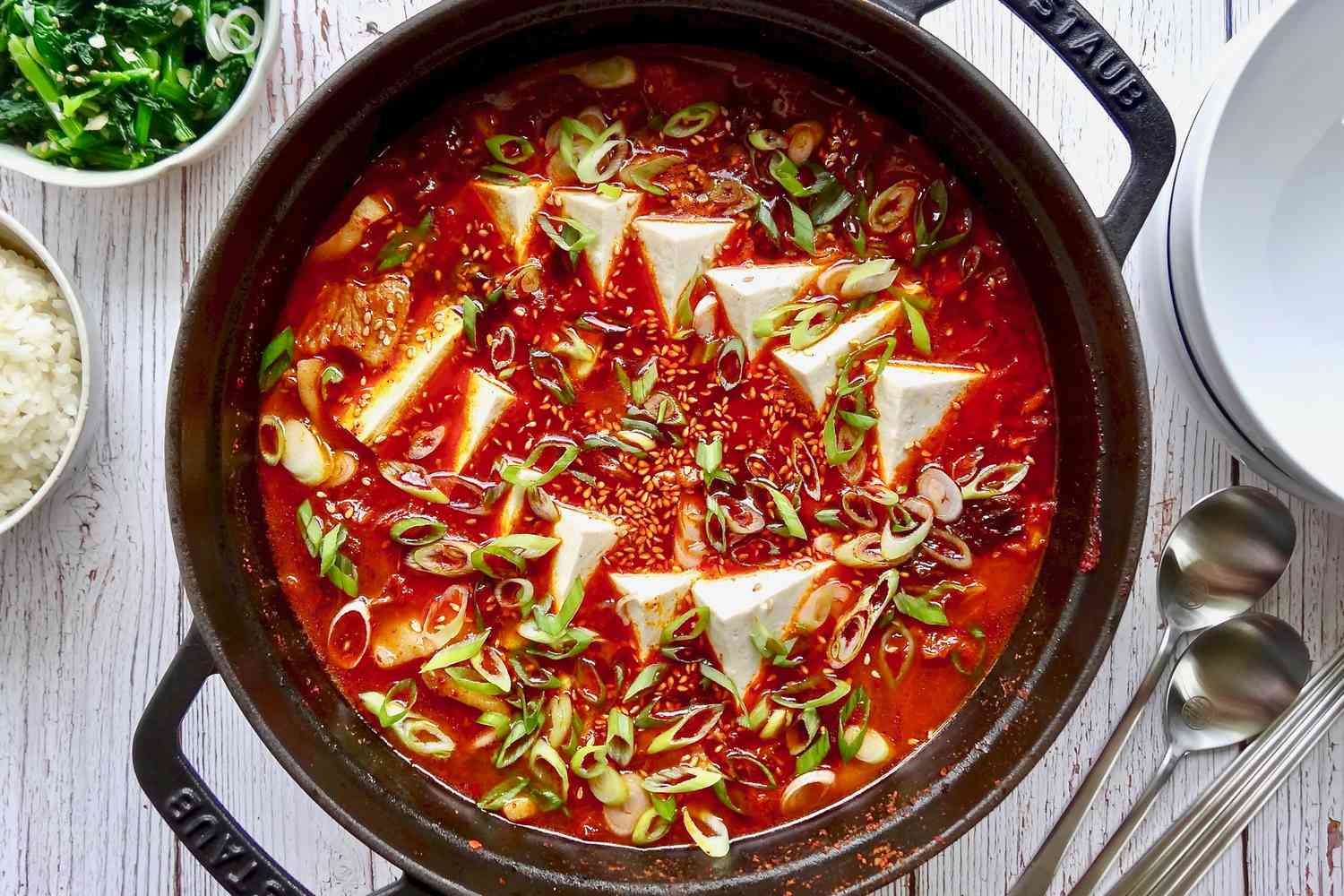 Overhead view of a dutch oven with pork belly and kimchi jjigae inside.