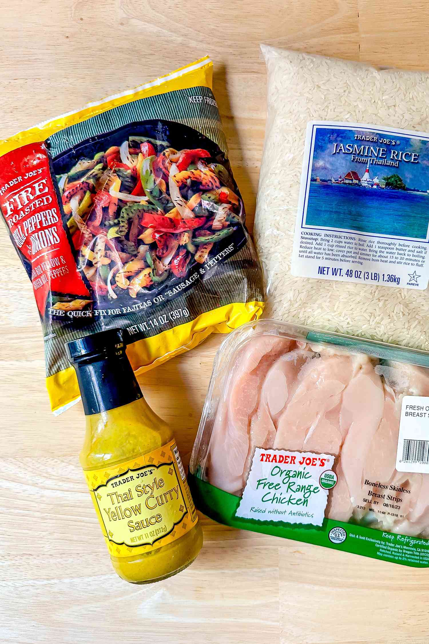 4-ingredient Trader Joe's chicken curry ingredients (L to R): packet of frozen fire roasted peppers, Trader Joe's Thai Style Yellow Curry Sauce, container of chicken breast, and a packet of jasmine rice