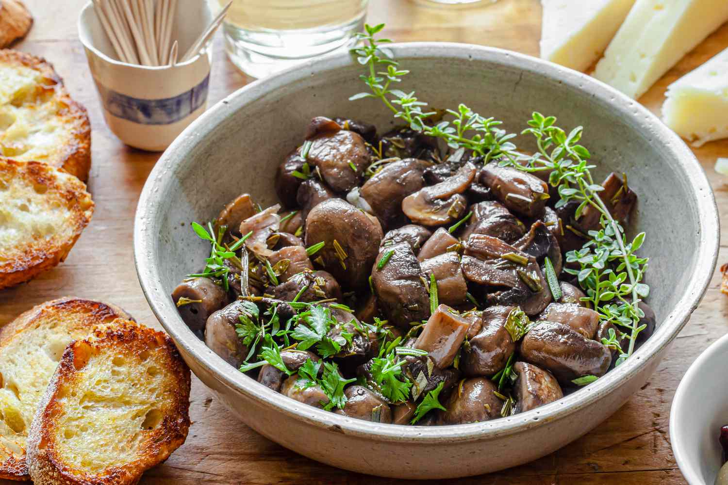 Marinated Mushrooms in a Bowl with Herbs and Surrounded by Crostini