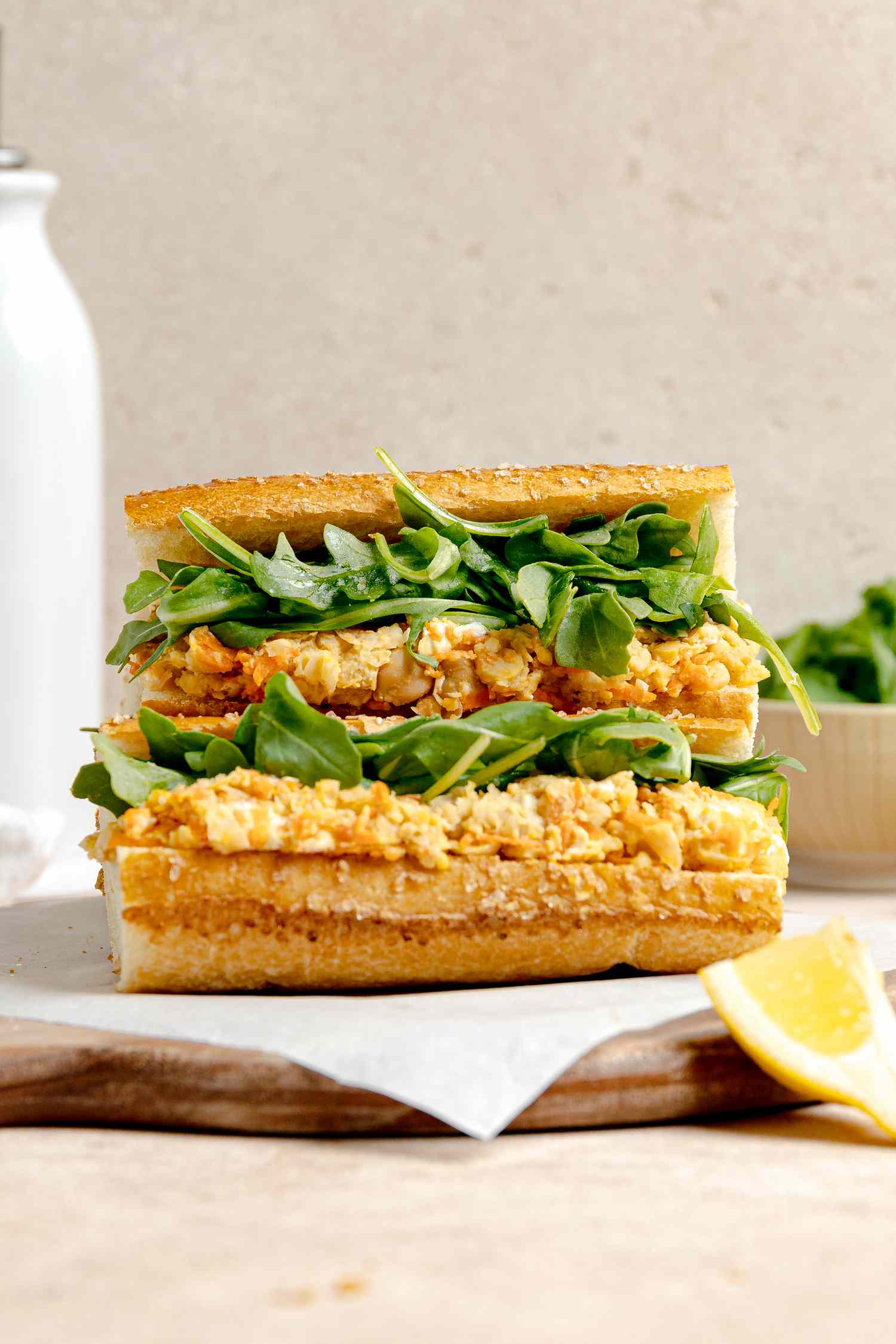 Chickpea Panini on Parchment Paper over Wooden Board with a Lemon Wedge Next to It