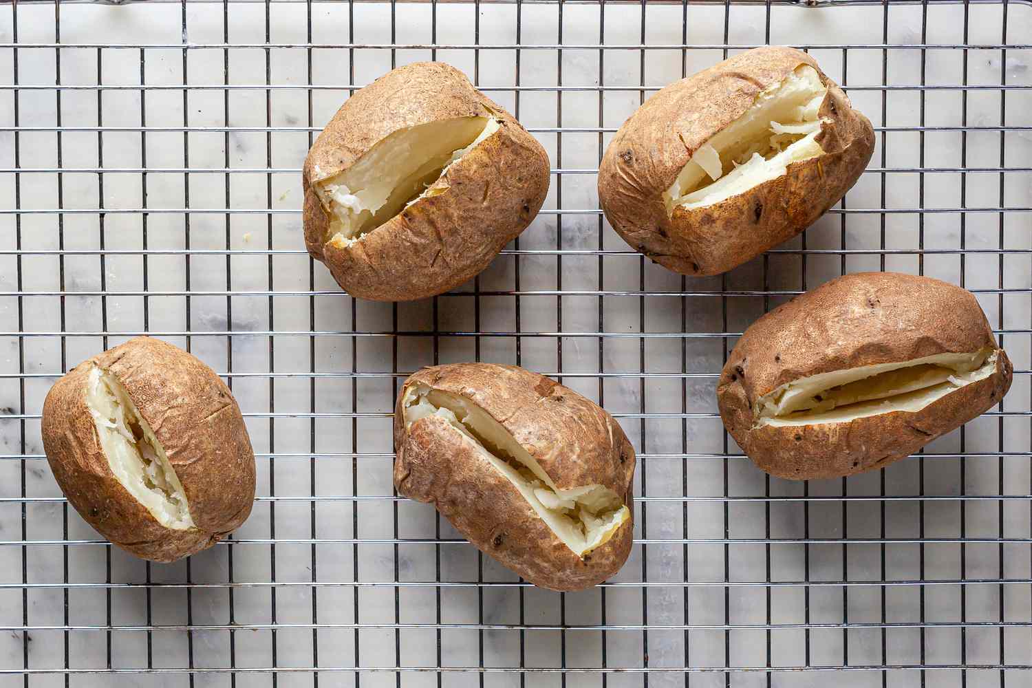 Baked russet potatoes cooling on a rack to make Potato Gnocchi