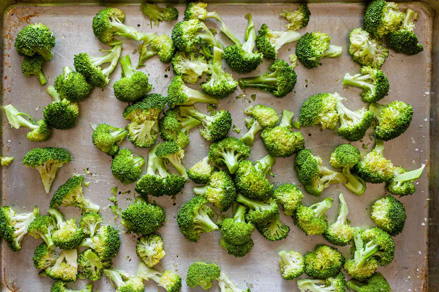 Overhead view of broccoli florets on a sheet pan.