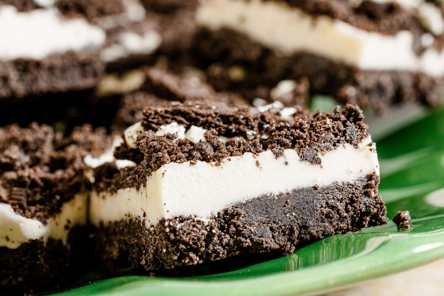 Closeup of dessert bars with a layer of crumbly cookie crust white filling and more crumbled cookies on top