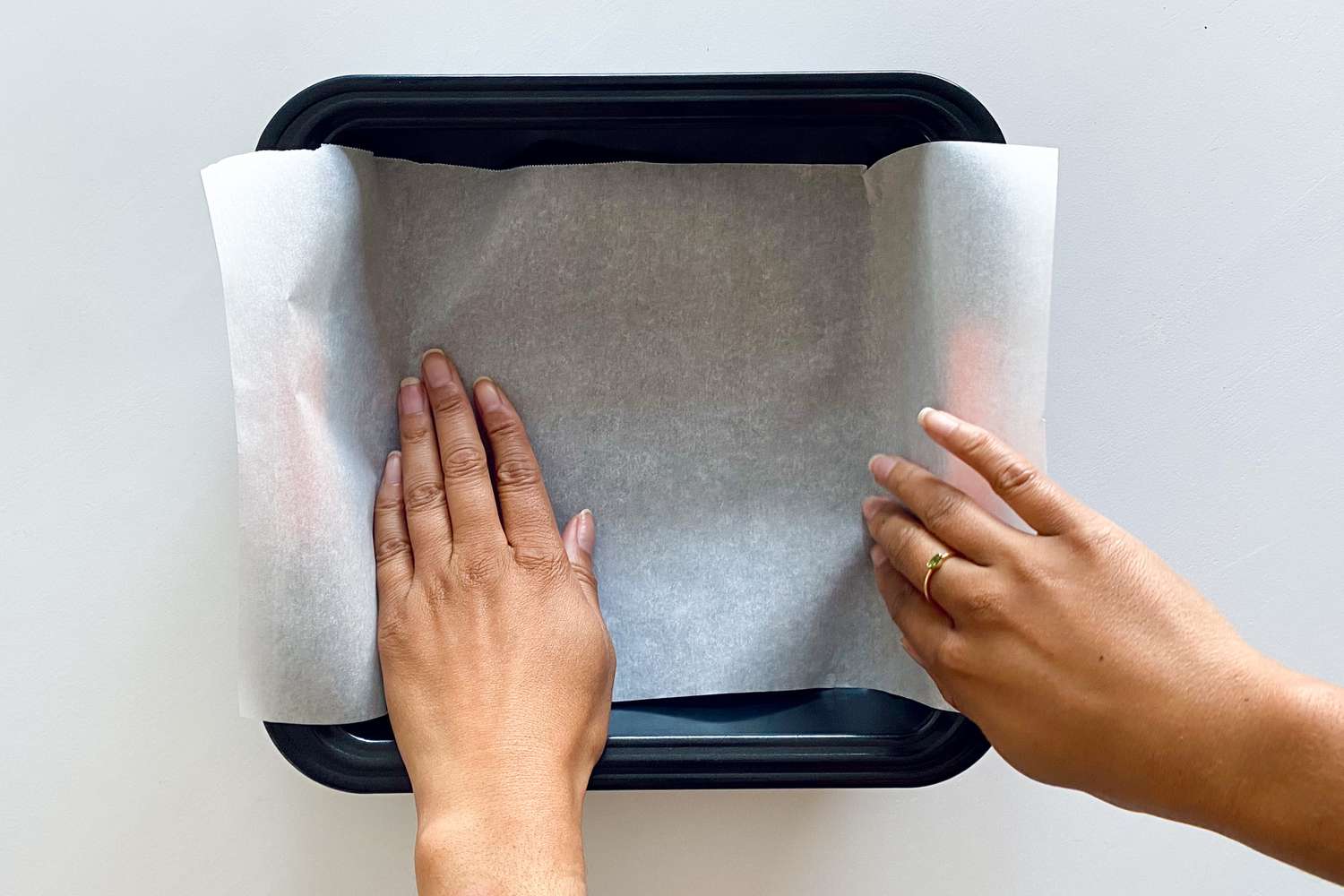 Lining a square pan with parchment to make Chewy Fruit and Nut Granola Bars.