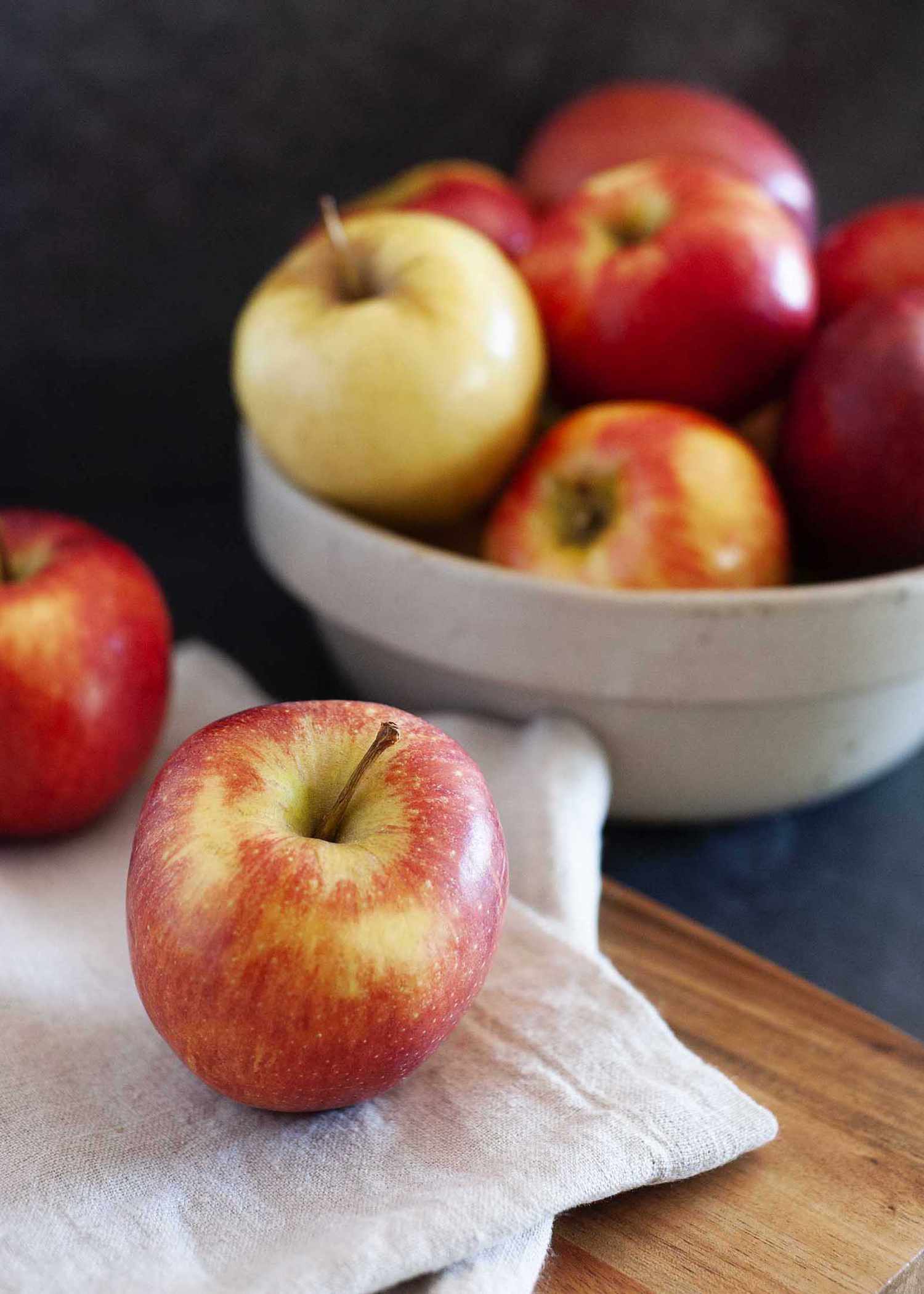 Guide to fall apples with apples on a counter and in a ceramic bowl.