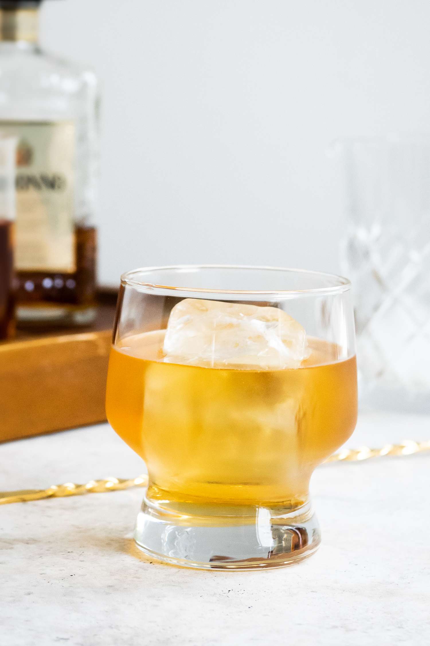 Godfather Cocktail Next to a Cocktail Spoon and a Tray with Ingredients