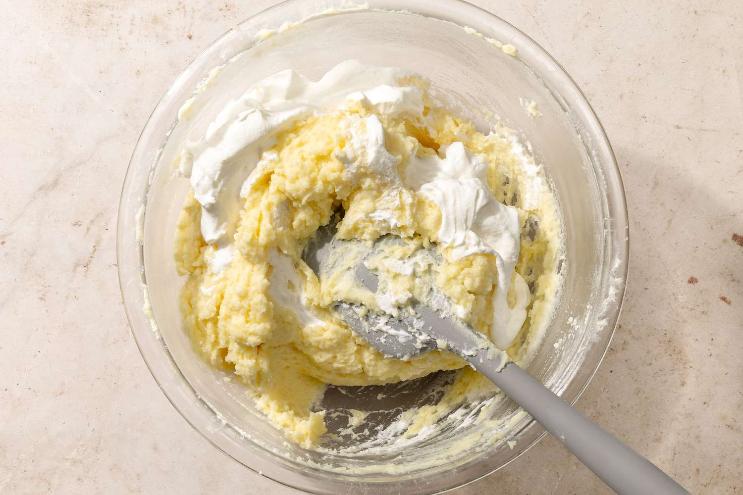 spatula folding in whipped cream to the potato puree in a bowl for Chantilly Potatoes