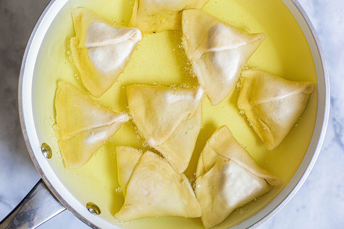 Pot of oil with samosas being fried.