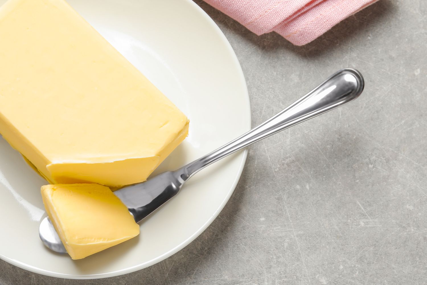 A block of softened butter on a plate with a butter spreader