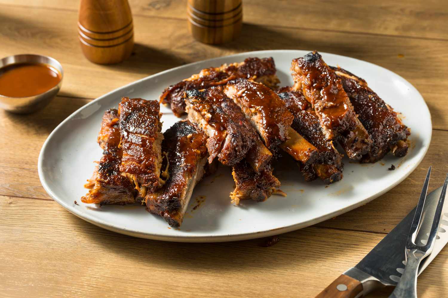 Barbecued baby back ribs cut up on a plate on a wooden table
