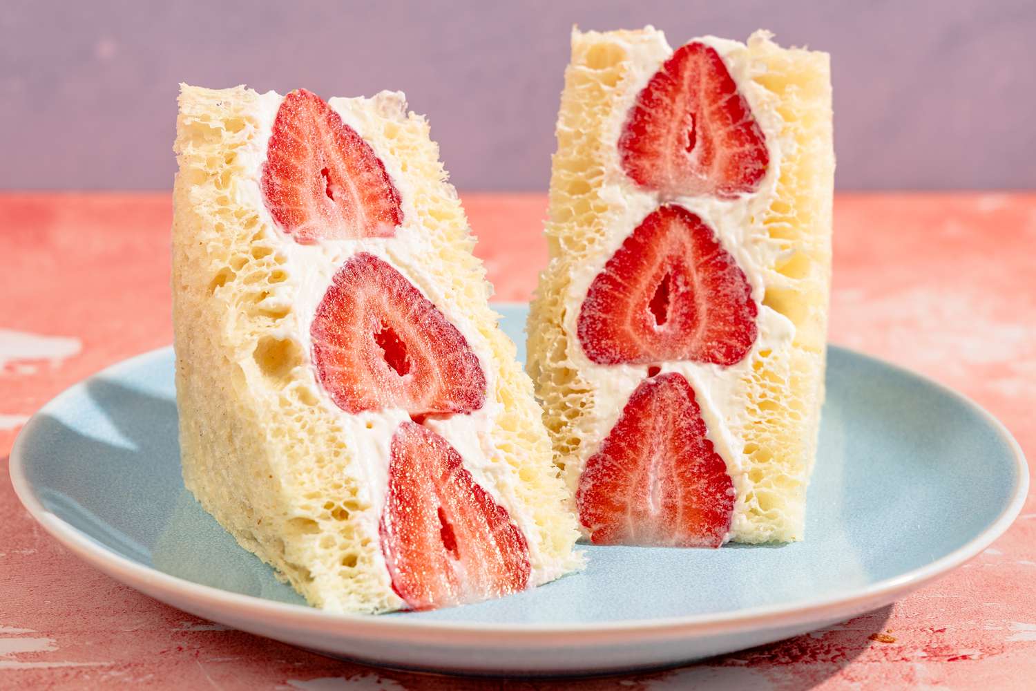 Two Japanese fruit sandos filled with strawberries and cream on a plate