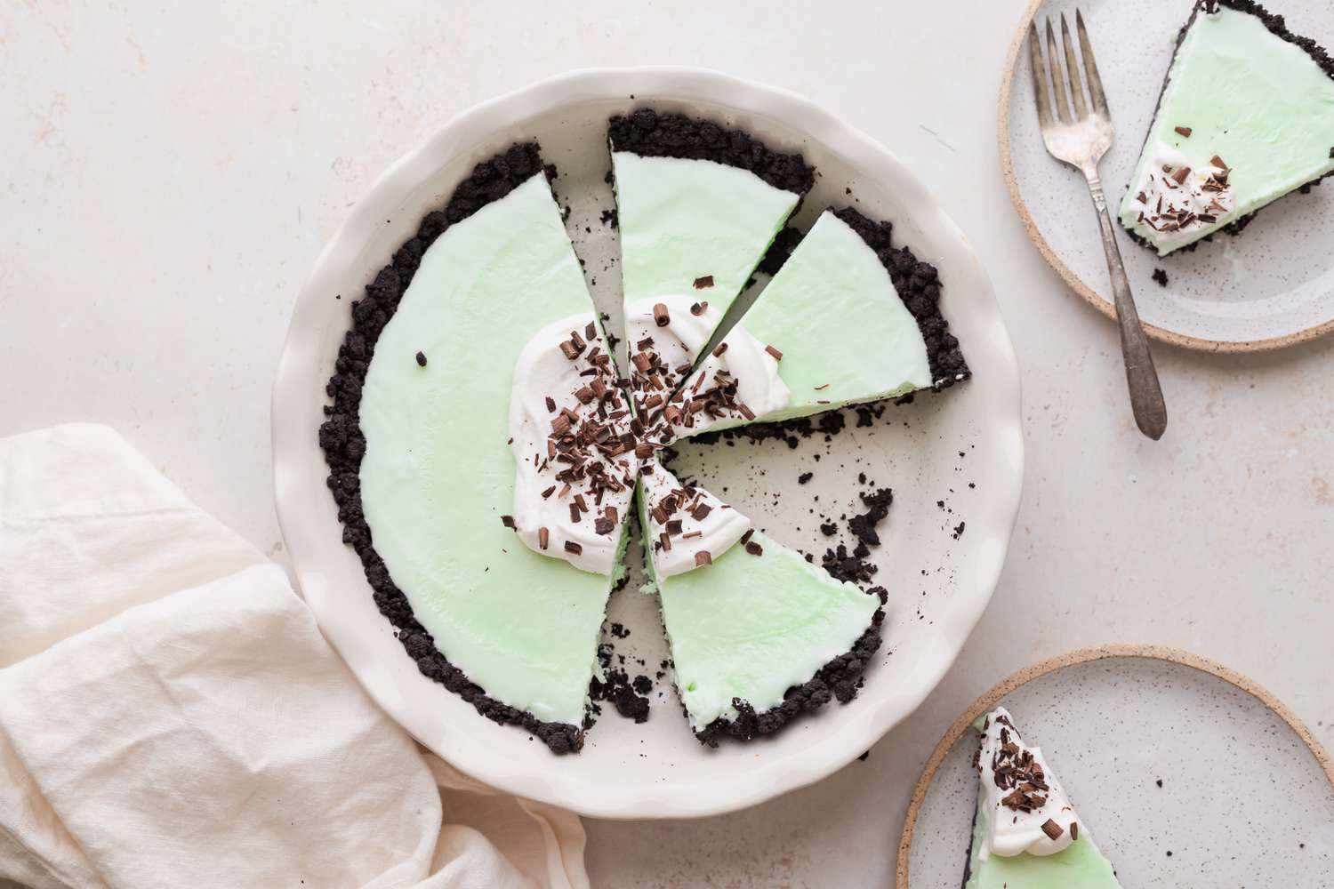 Overhead view of grasshopper pie cut into slices with one on a plate.