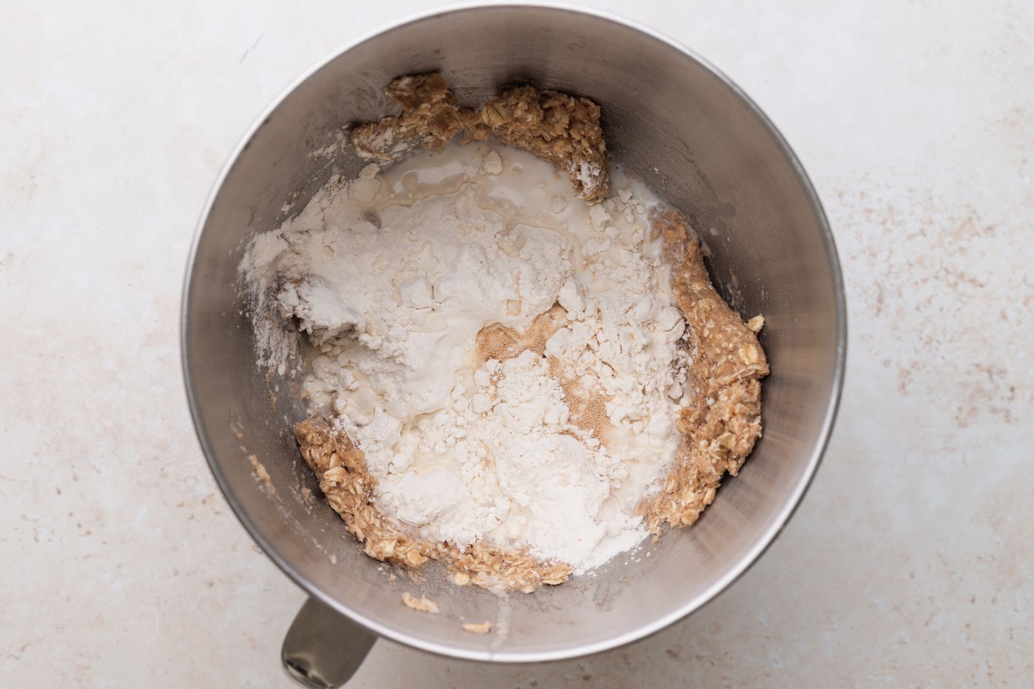 Overhead view of a metal bowl with ingredients to show how to make oat bread.