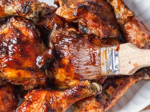 Brushing bbq sauce on barbecue chicken.
