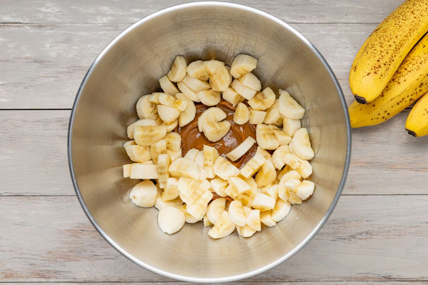Sliced Bananas and Dulce de Leche in a Mixer Bowl, and on the Counter, a Bunch of Bananas