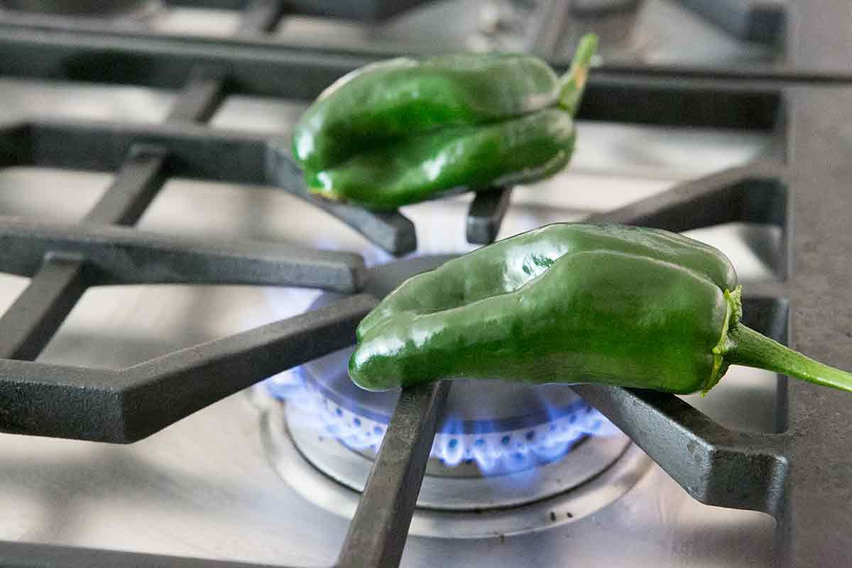 char poblano peppers over an open flame for rajas con crema