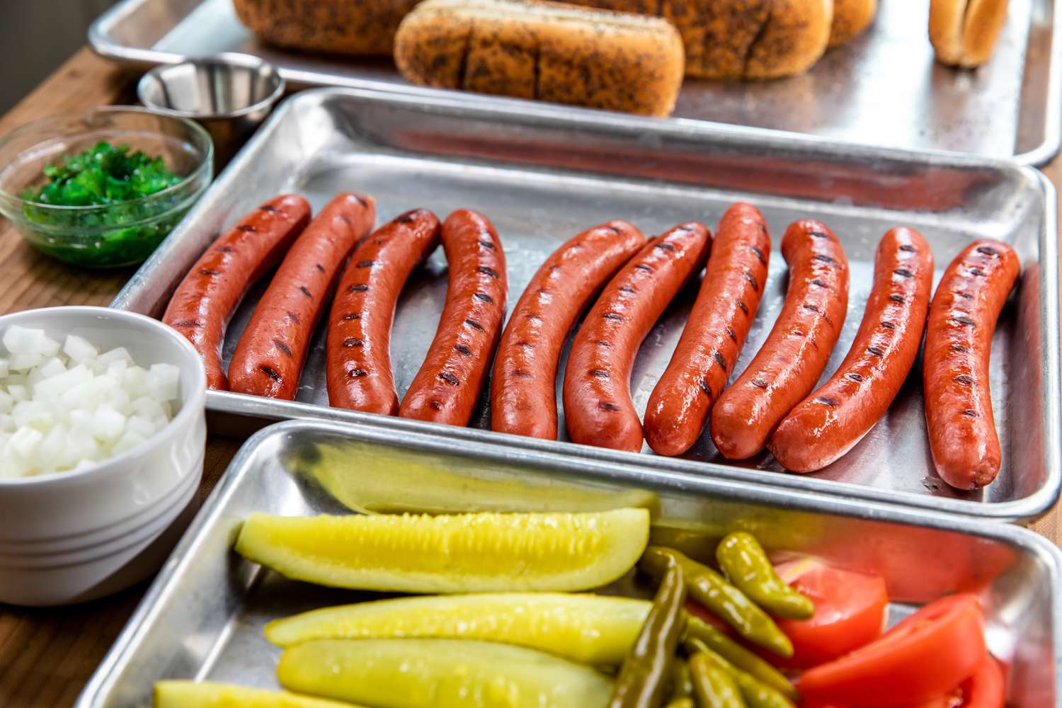 All-beef hot dog with toppings prepped on sheet pans.