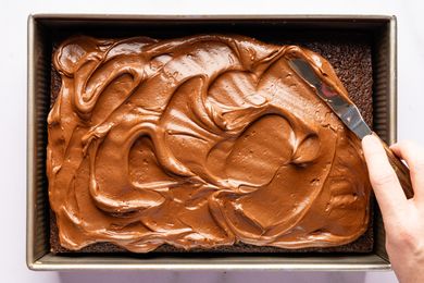 Overhead view of spreading the whipped ganache on the cooled cake for Easy Brooklyn Blackout Cake recipe