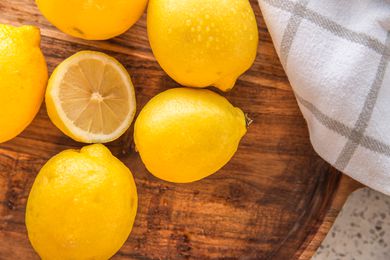 Overhead view of lemons on a wooden surface, one of the lemons cut in half