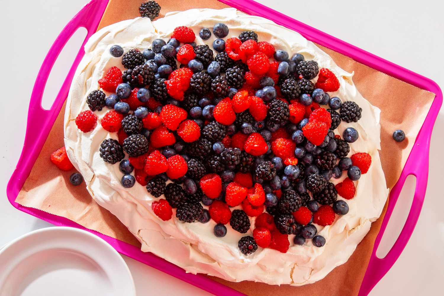 berry pavlova on a parchment paper lined tray
