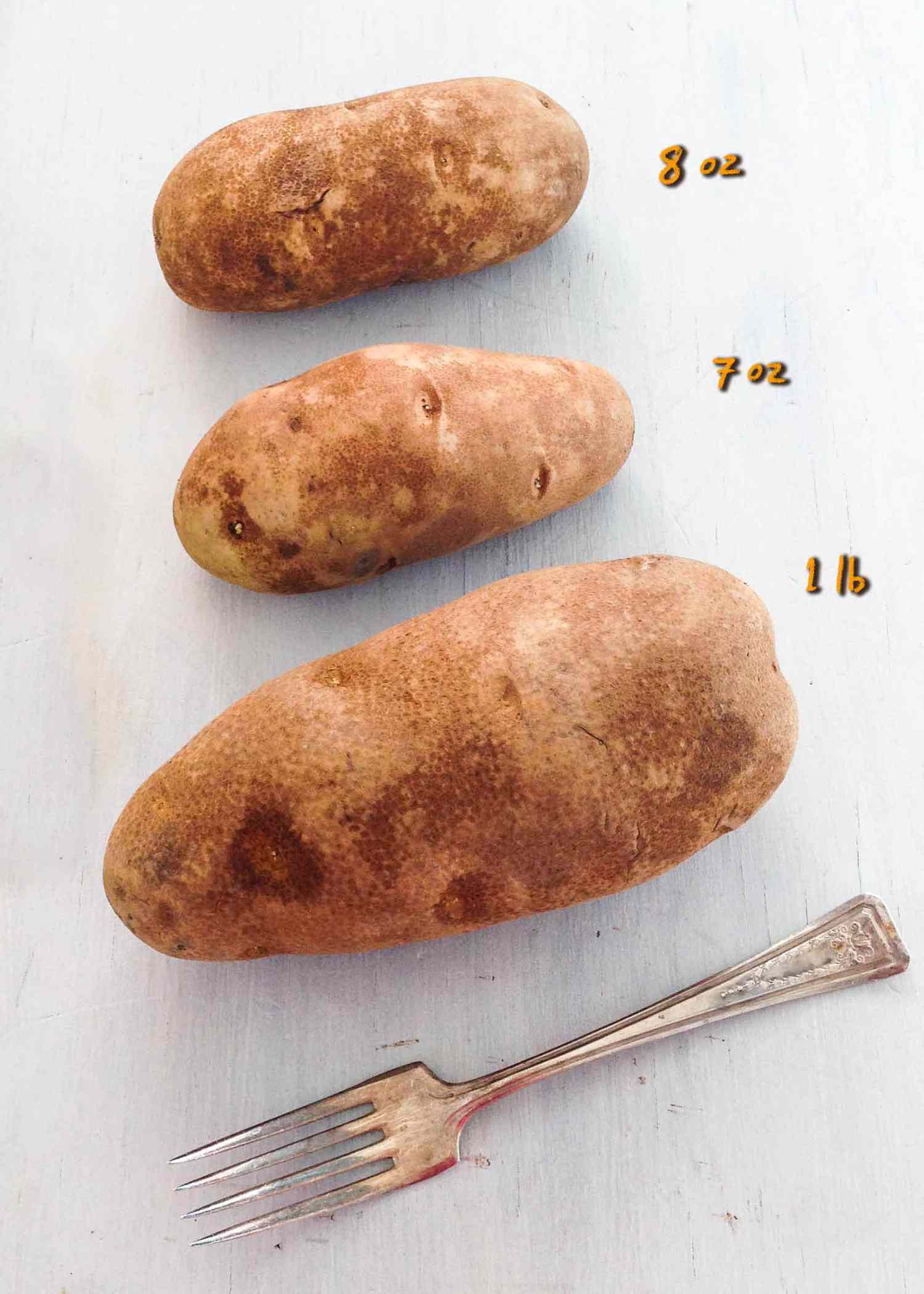 Three potatoes lined up showing sizes with the top being eight ounces, the middle being seven ounces, and the bottom being one pound. 