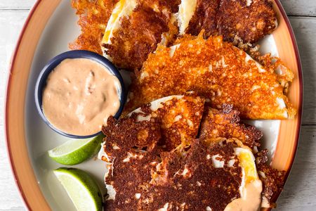 Burnt Cheese Tacos on a Plate with Chipotle Sauce and Lime Wedges