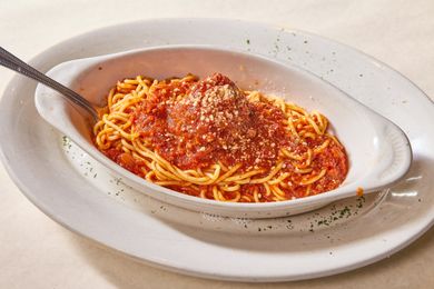 A dish of spaghetti with tomato sauce and parmesan cheese served on a white plate