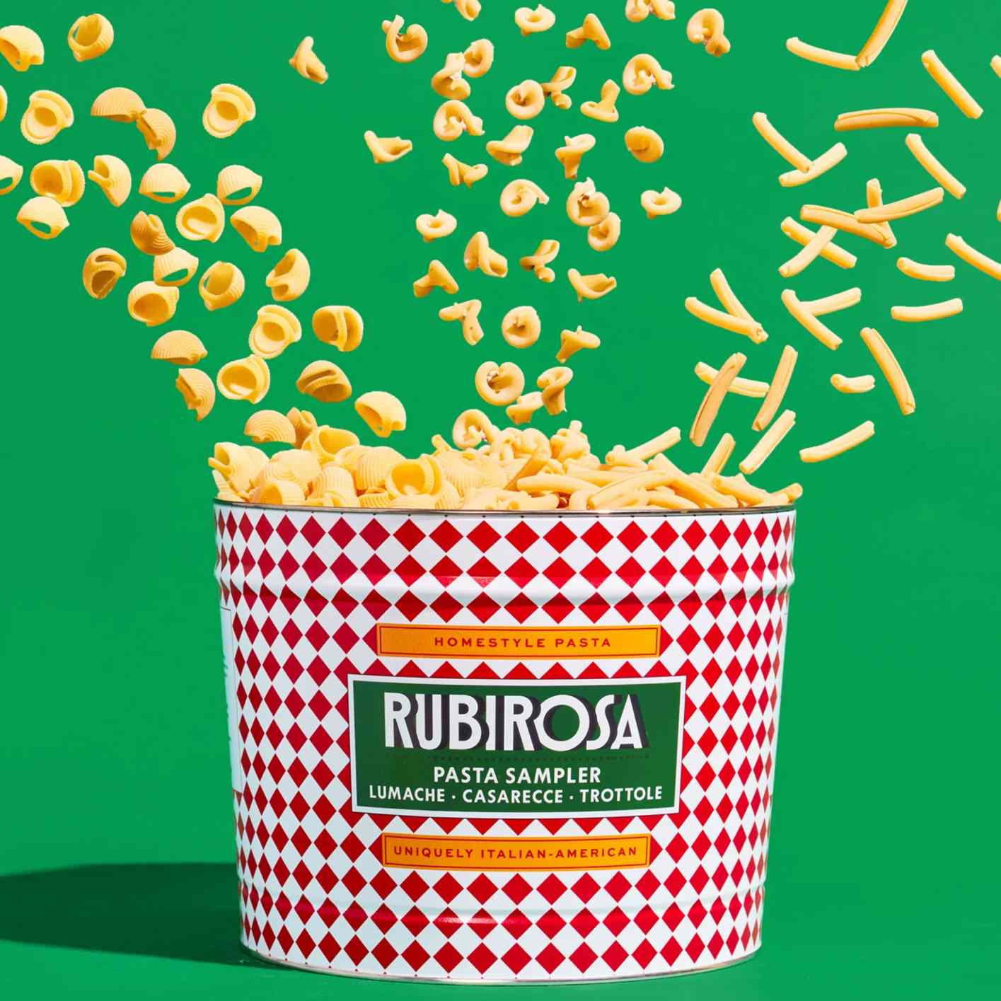 Pasta flying out of a red and white container labeled Rubirosa Pasta Sampler