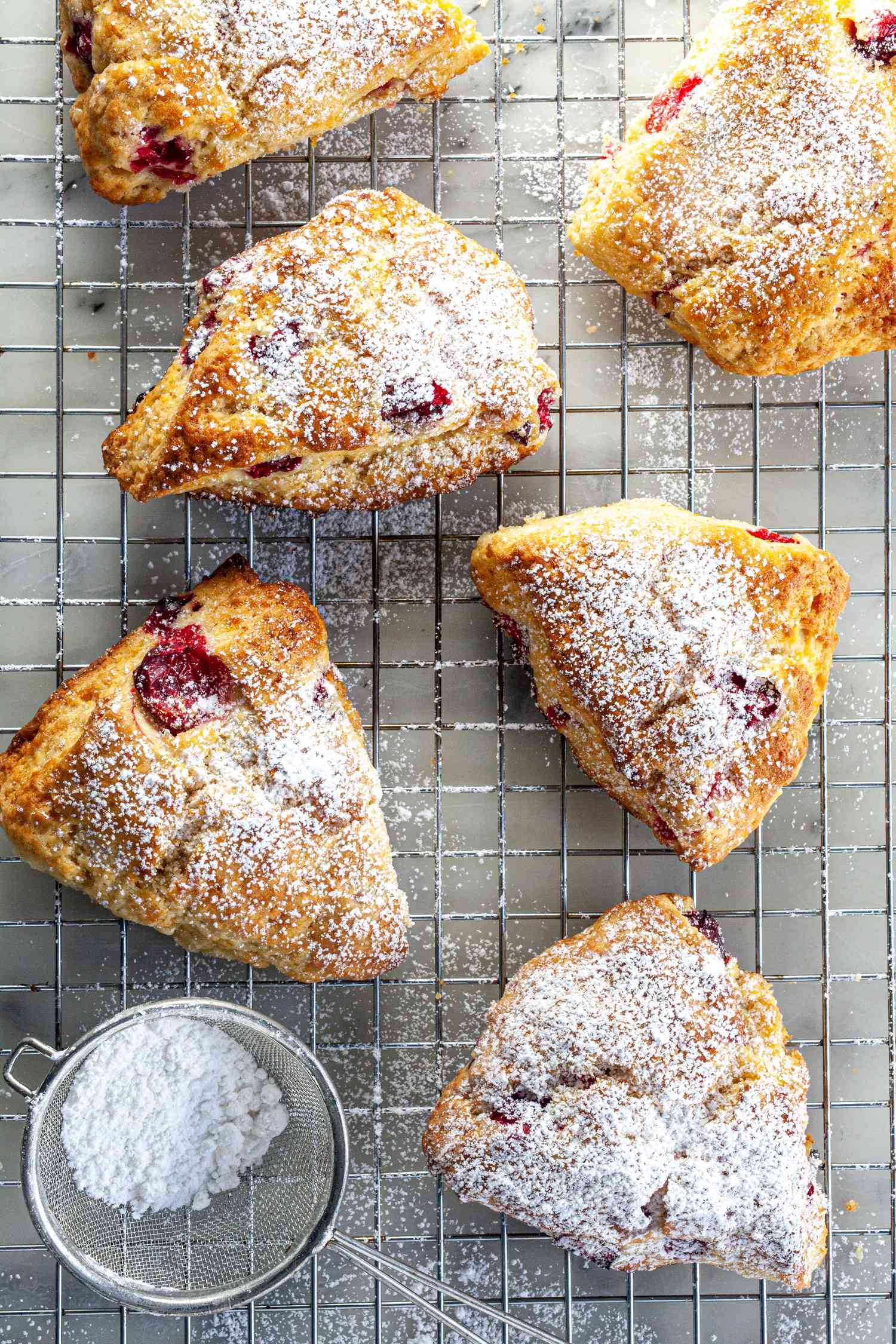 Orange cranberry scones on rack with dusting of powdered sugar.