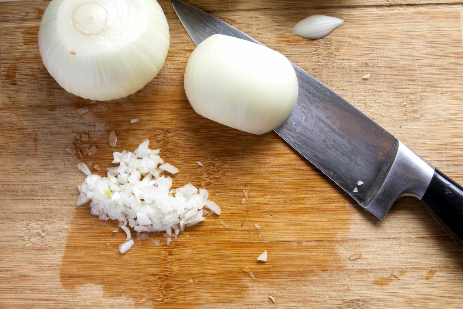 Chopped and whole onions on a cutting board with a knife