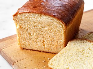 Brioche Sandwich Loaf on a Cutting Board with Slices of Bread Cascading Off the Board onto the Counter