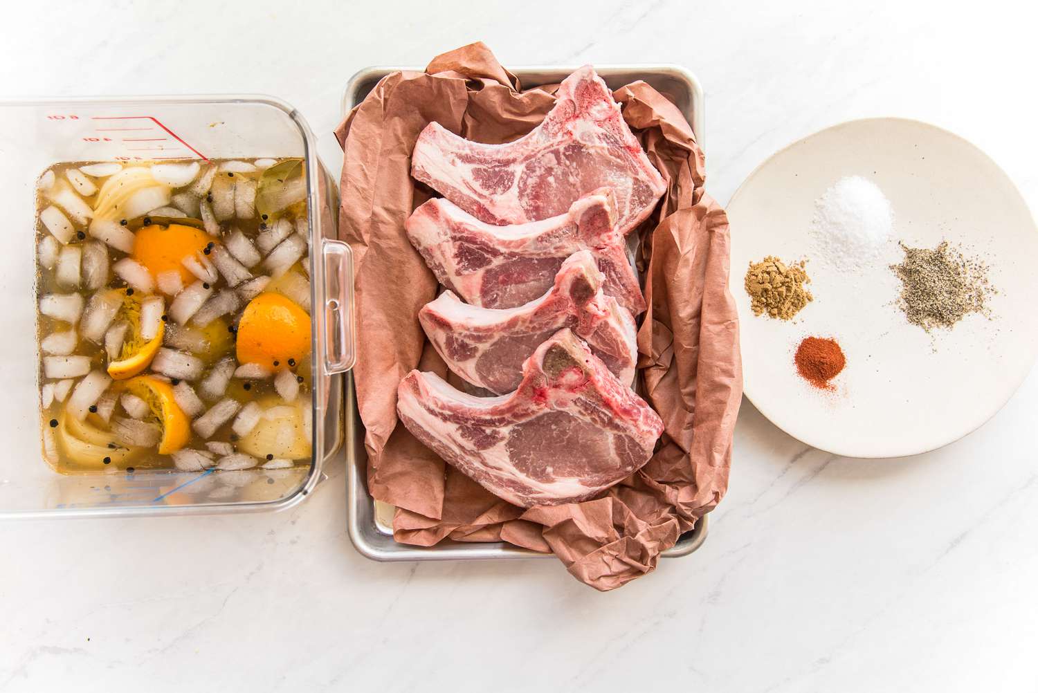 Tray of Pork Chops Next to Pork Chop Brine and Plate of Spices