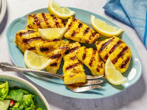 Grilled chicken pieces with lemon wedges on a plate