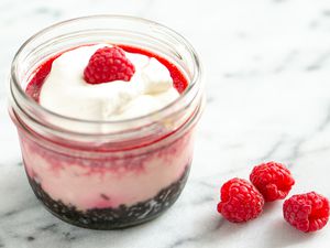 Raspberry cheesecake in a jar topped with whipped cream and fresh raspberry