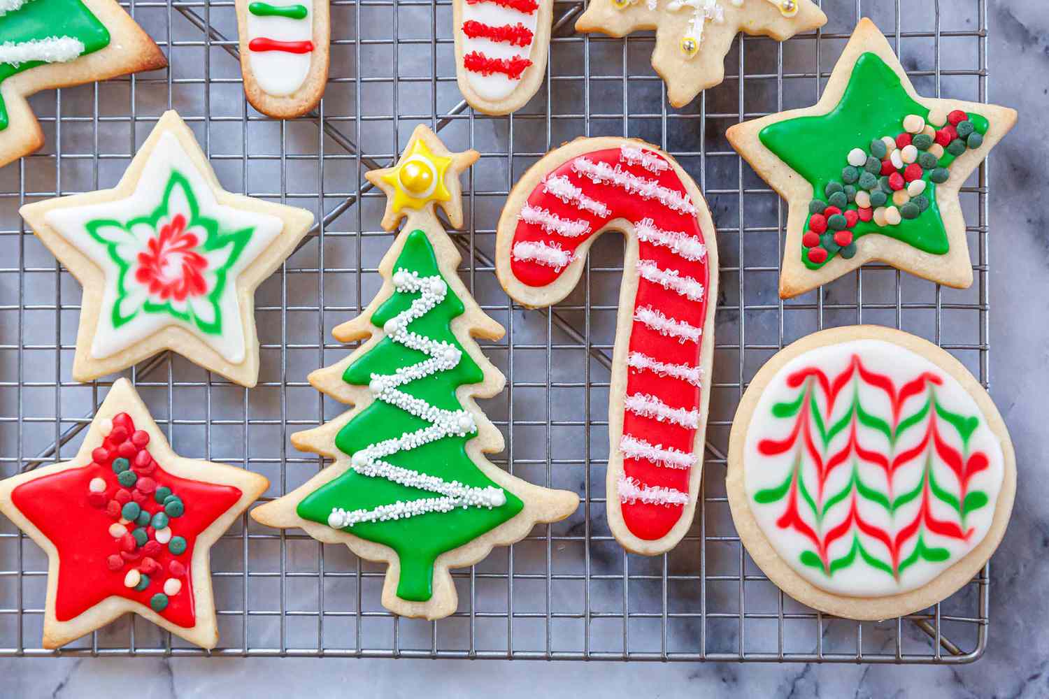 Cooling rack with festive cookies decorated with Royal icing and sprinkles.