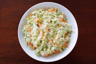 A bowl of coleslaw placed on a wooden surface