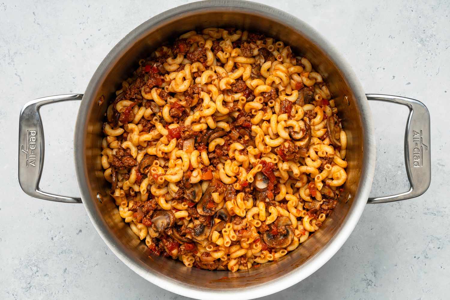 Johnny Marzetti casserole ingredients mixed together with cheese in a pot 